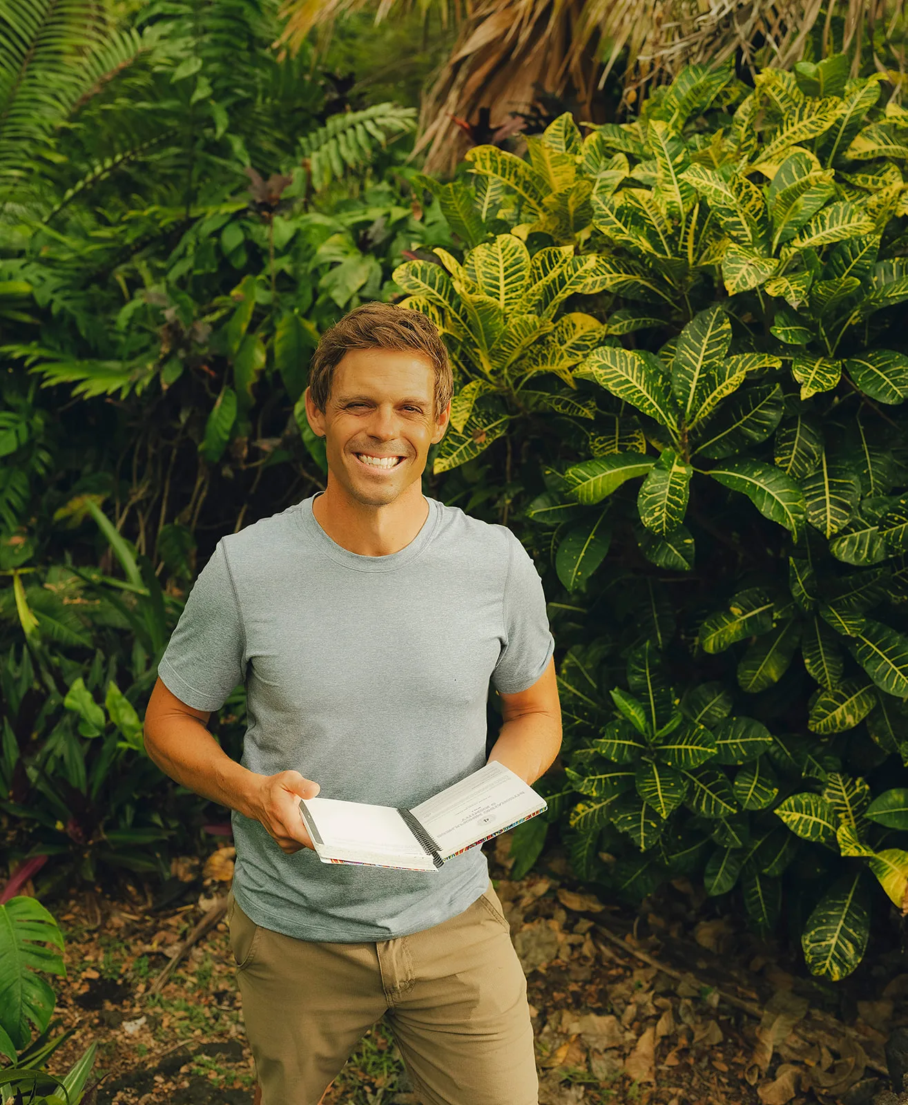 Seth holding an open journal in a tropical garden