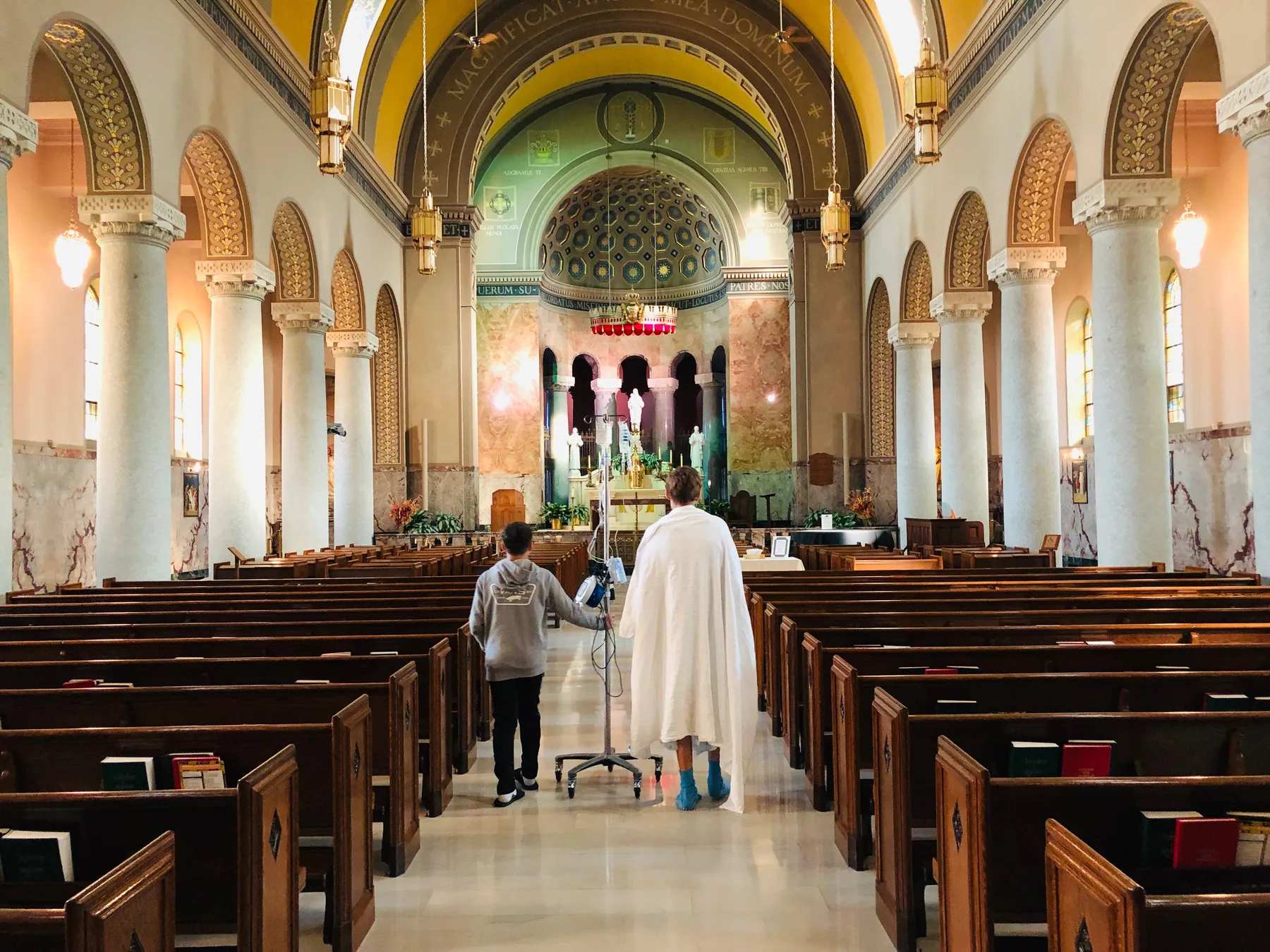 Seth walking through a chapel with an IV stand during cancer recovery